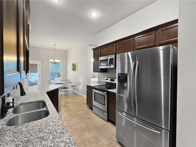 kitchen featuring sink, light stone counters, dark brown cabinets, hanging light fixtures, and stainless steel appliances