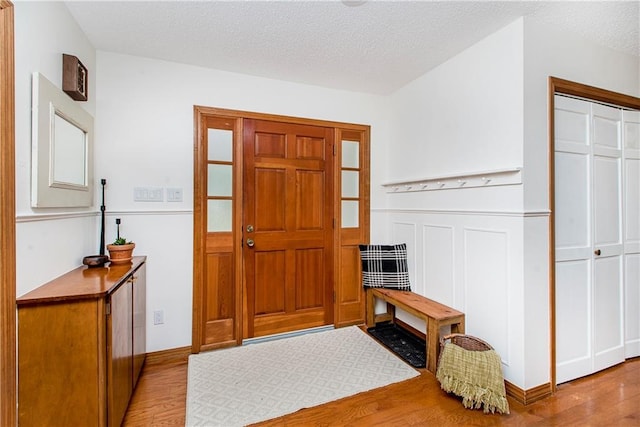 foyer entrance featuring a textured ceiling and light wood-type flooring