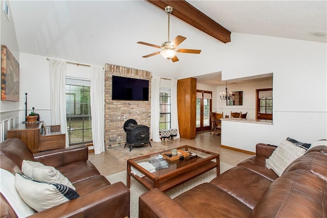 living room with a healthy amount of sunlight, beam ceiling, ceiling fan with notable chandelier, and a wood stove