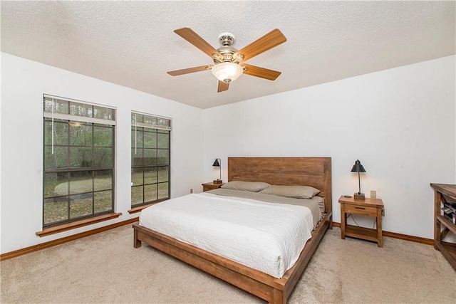 bedroom with ceiling fan, light colored carpet, and a textured ceiling