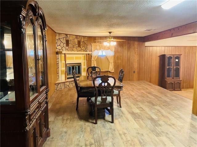 dining area featuring wooden walls, a fireplace, hardwood / wood-style floors, and a textured ceiling