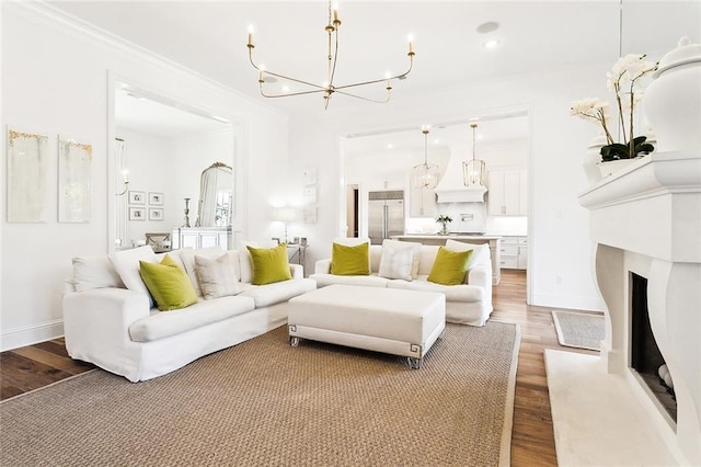 living room with crown molding, light wood-type flooring, and an inviting chandelier