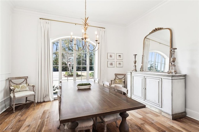 dining room featuring ornamental molding, light wood-type flooring, and a chandelier