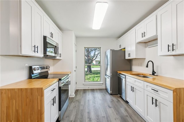 kitchen featuring stainless steel appliances, white cabinetry, and wood counters