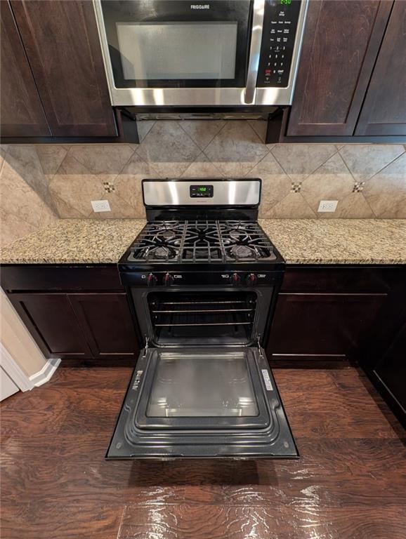 kitchen with light stone counters, dark brown cabinetry, and stainless steel appliances