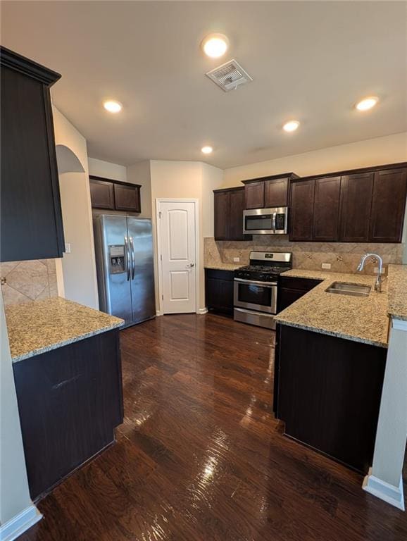 kitchen featuring dark wood-type flooring, dark brown cabinetry, sink, light stone counters, and stainless steel appliances