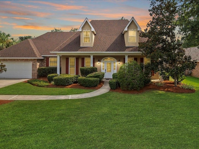 view of front of home featuring a garage, a porch, and a yard