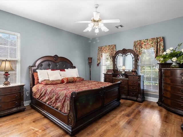 bedroom featuring multiple windows, hardwood / wood-style floors, and ceiling fan