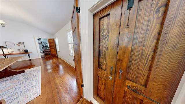 hall with wood-type flooring and lofted ceiling