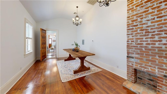 interior space featuring hardwood / wood-style flooring, a fireplace, a chandelier, and vaulted ceiling