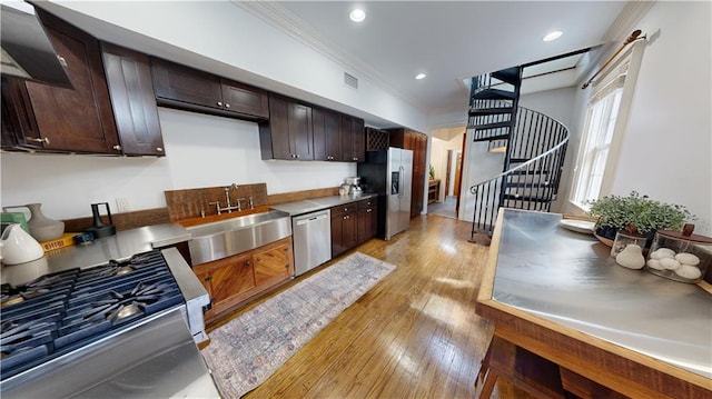 kitchen with sink, stainless steel counters, light hardwood / wood-style floors, stainless steel appliances, and dark brown cabinets