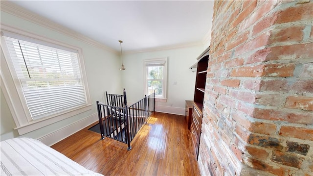 stairs with brick wall, ornamental molding, and wood-type flooring