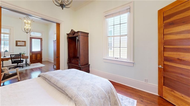 bedroom with an inviting chandelier, dark hardwood / wood-style flooring, multiple windows, and crown molding