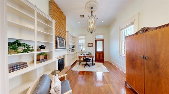 home office with crown molding, an inviting chandelier, a fireplace, and hardwood / wood-style floors