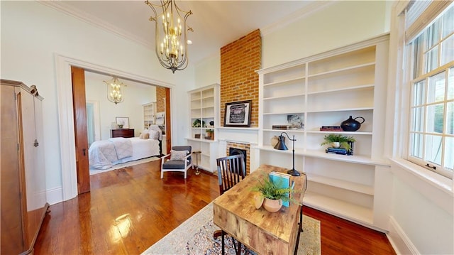 interior space with crown molding, a brick fireplace, dark hardwood / wood-style floors, and an inviting chandelier