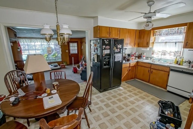 kitchen with dishwashing machine, sink, pendant lighting, ceiling fan with notable chandelier, and black refrigerator with ice dispenser