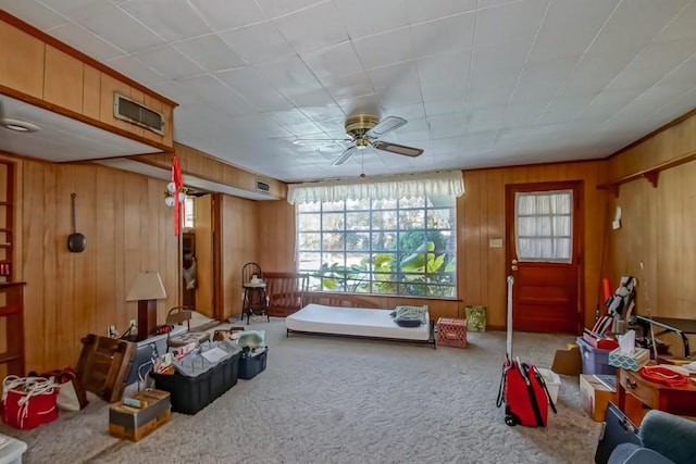 interior space with carpet flooring, ceiling fan, and wood walls