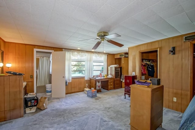 miscellaneous room featuring light carpet, wooden walls, and ceiling fan