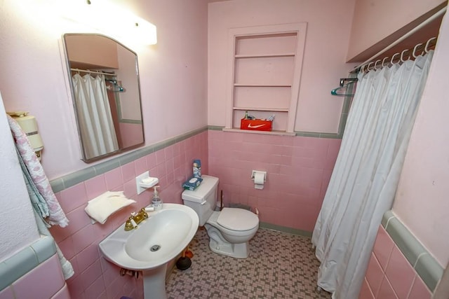 bathroom with toilet, sink, and tile walls