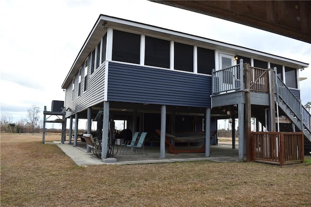 rear view of house with a sunroom, a patio area, and a lawn