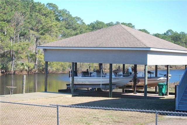 view of dock featuring a water view, boat lift, and fence