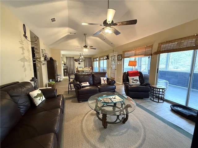 living room featuring plenty of natural light, visible vents, and vaulted ceiling