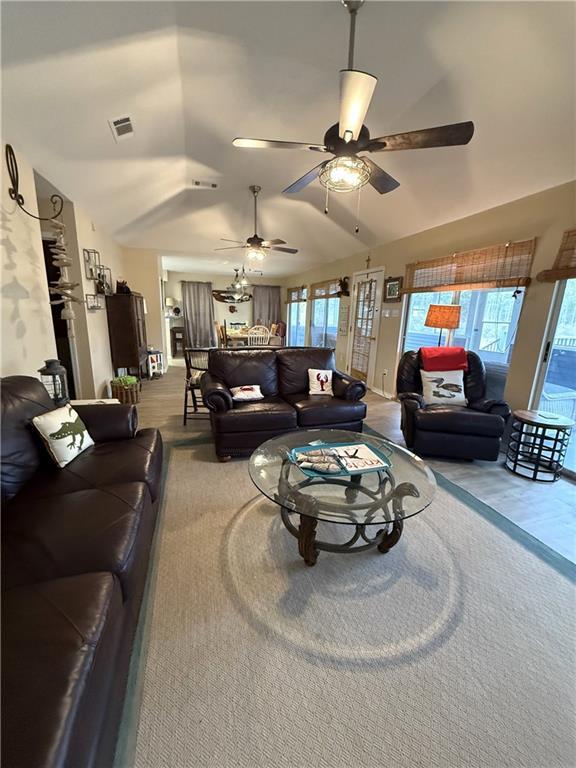 living room featuring lofted ceiling, plenty of natural light, visible vents, and ceiling fan