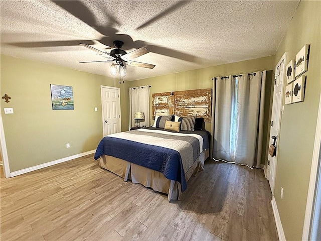 bedroom with ceiling fan, a textured ceiling, baseboards, and wood finished floors