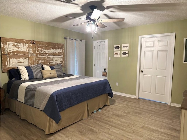 bedroom featuring a textured ceiling, ceiling fan, light wood-type flooring, and baseboards