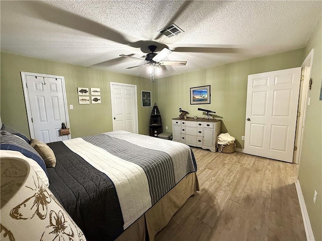 bedroom featuring a textured ceiling, light wood finished floors, visible vents, and baseboards