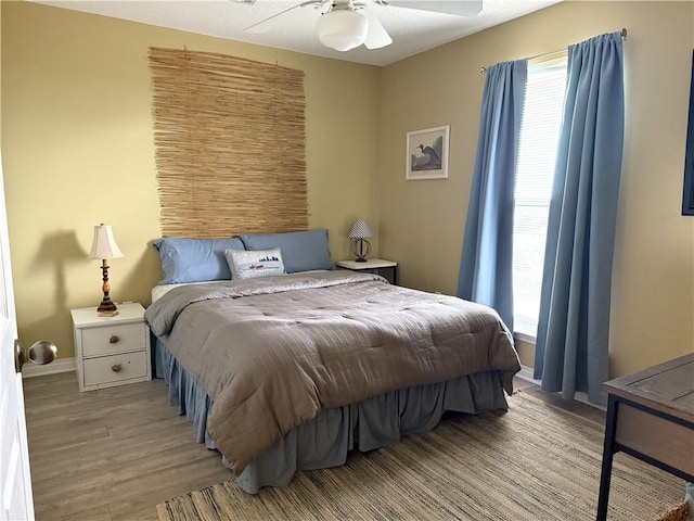 bedroom with a ceiling fan, light wood-type flooring, multiple windows, and baseboards