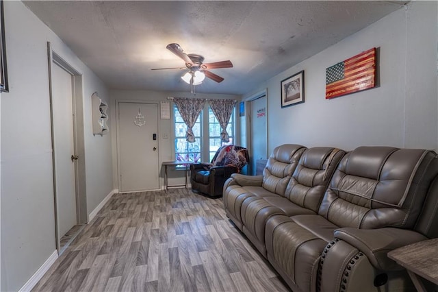 living room with ceiling fan, light hardwood / wood-style flooring, and a textured ceiling