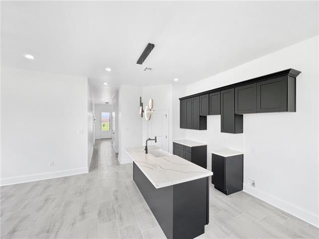 kitchen featuring light stone counters, sink, an island with sink, and light wood-type flooring