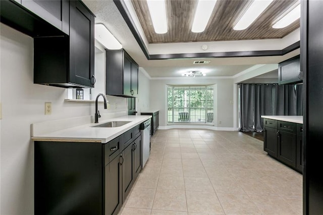 kitchen with sink, a tray ceiling, ornamental molding, light tile patterned flooring, and stainless steel dishwasher