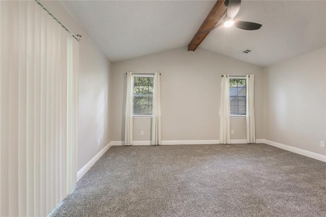 empty room with plenty of natural light, carpet flooring, and vaulted ceiling with beams