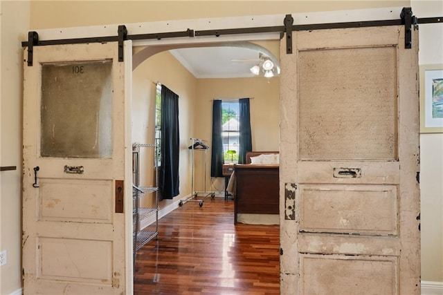 interior space with ornamental molding, a barn door, and dark hardwood / wood-style flooring