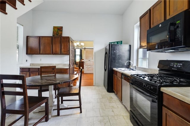 kitchen with sink, black appliances, and a chandelier