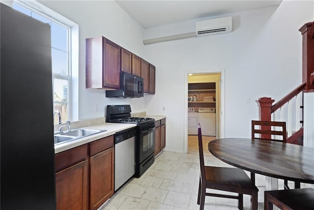 kitchen featuring separate washer and dryer, sink, an AC wall unit, and black appliances