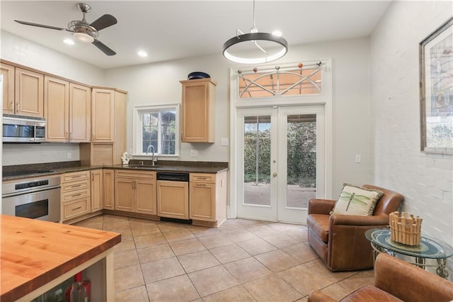 kitchen with butcher block countertops, light tile patterned floors, sink, appliances with stainless steel finishes, and french doors