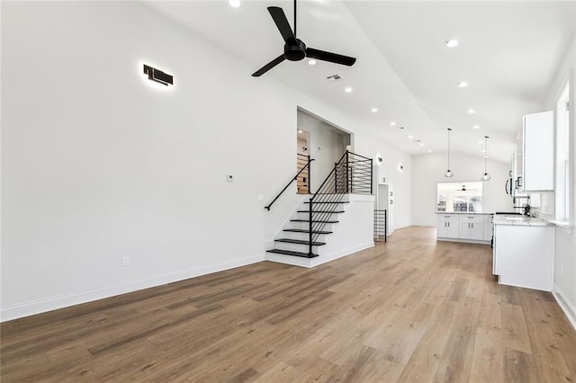 unfurnished living room with light hardwood / wood-style flooring, high vaulted ceiling, and ceiling fan