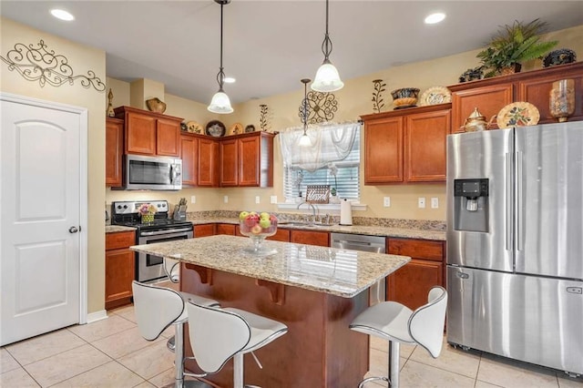 kitchen with decorative light fixtures, a kitchen breakfast bar, a kitchen island, stainless steel appliances, and light stone countertops