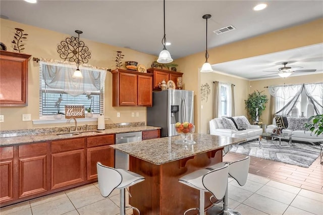 kitchen with sink, stainless steel appliances, hanging light fixtures, and a kitchen bar