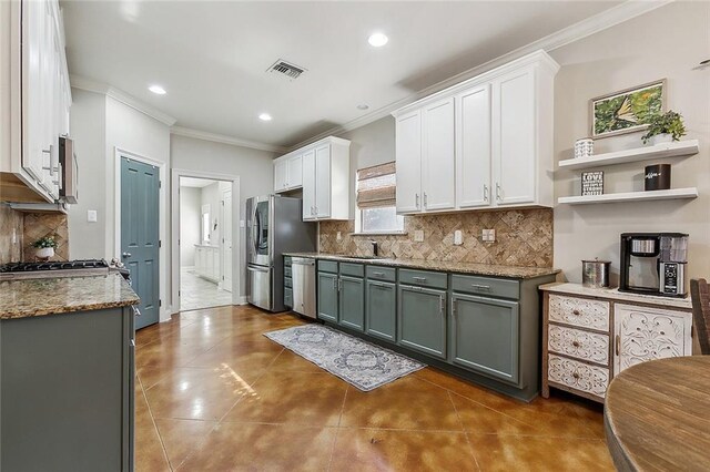 kitchen with backsplash, appliances with stainless steel finishes, dark tile patterned floors, and white cabinets