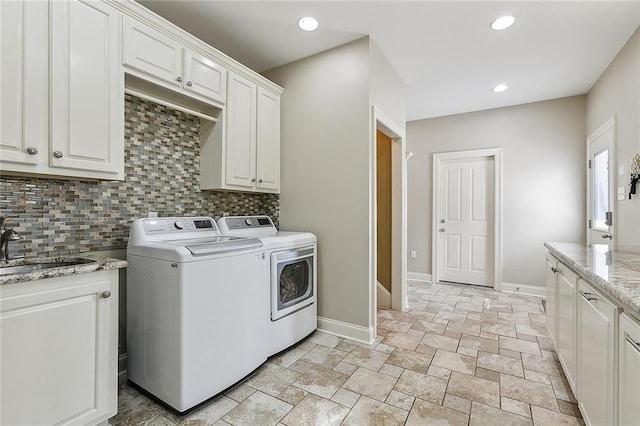 clothes washing area featuring cabinets, washer and dryer, and sink