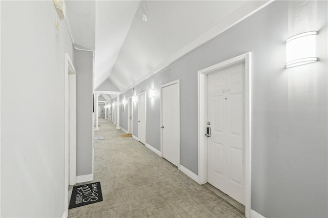 corridor with light carpet and vaulted ceiling