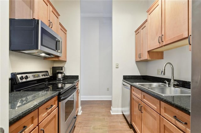 kitchen featuring sink, light hardwood / wood-style flooring, dark stone countertops, ornamental molding, and appliances with stainless steel finishes