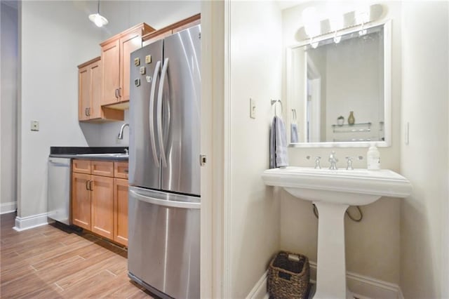 kitchen featuring sink, light hardwood / wood-style flooring, stainless steel appliances, and hanging light fixtures