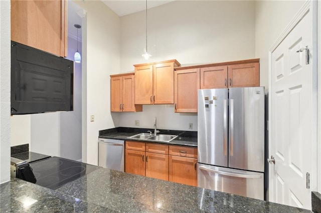 kitchen featuring pendant lighting, appliances with stainless steel finishes, sink, and dark stone countertops