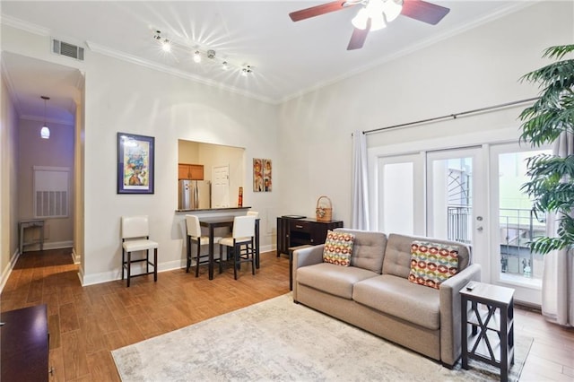 living room featuring ornamental molding, wood-type flooring, rail lighting, and plenty of natural light