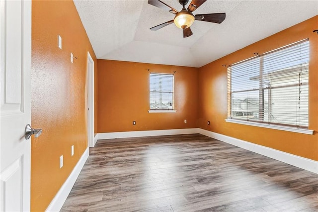 spare room featuring ceiling fan, dark wood-type flooring, a wealth of natural light, and a textured ceiling